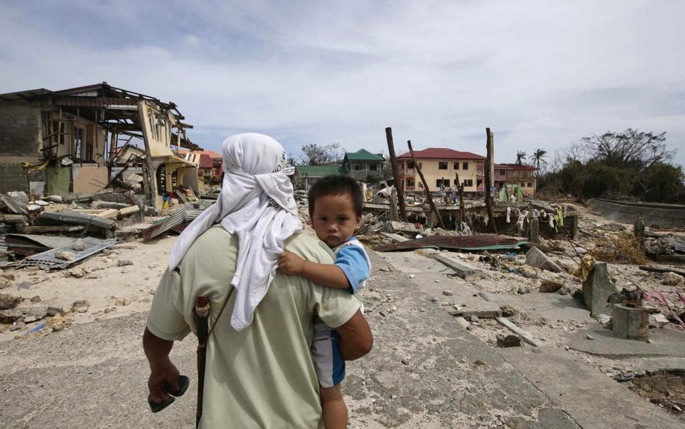 A man walks home with his son Monday Nov. 11, 2013 following Friday&#039;s devastating typhoon that lashed Hernani township, Eastern Samar province, central Philippines. (Bullit Marquez/AP)