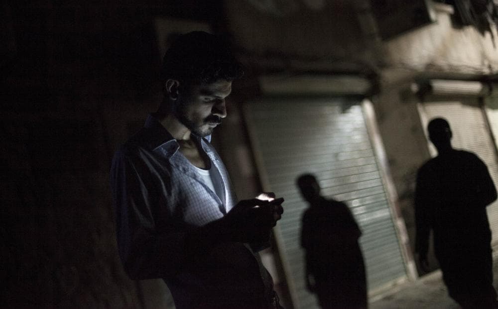 To communicate safely under an authoritarian regime requires a sort of linguistic creativity. In this photo, a man looks at his phone in Aleppo, Syria, in September 2012. (Manu Brabo/AP)