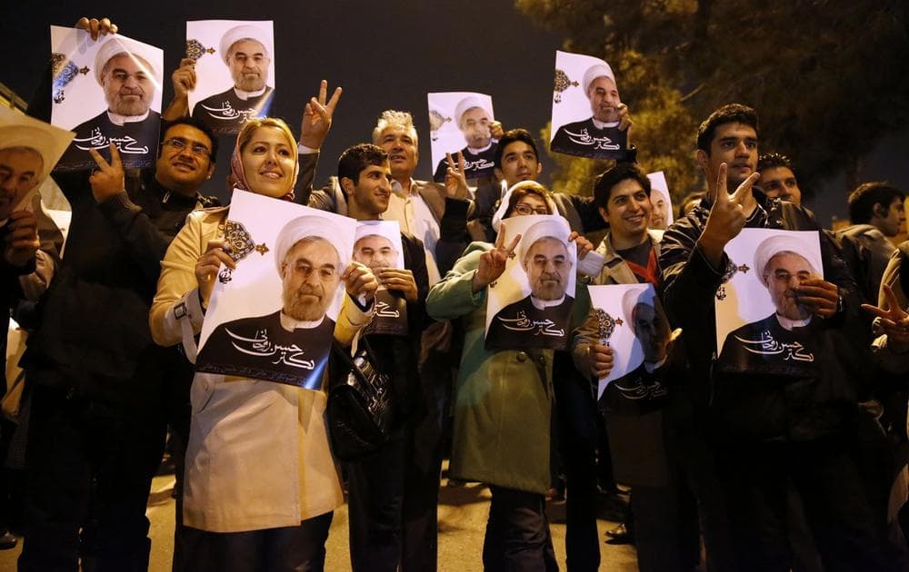 In this photo released by the Iranian Students News Agency, ISNA, Iranians hold posters of President Hassan Rouhani as they welcome Iranian nuclear negotiators upon their arrival from Geneva at the Mehrabad airport in Tehran, Iran, Sunday, Nov. 24, 2013. (Hemmat Khahi/ISNA via AP)