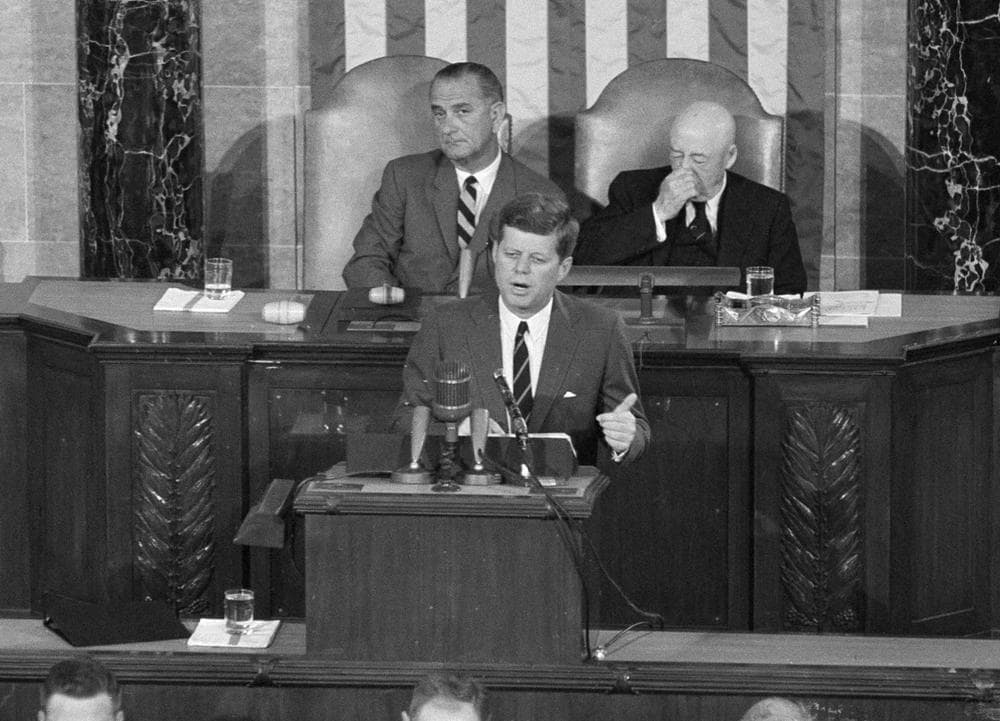 In this May 25, 1961, file photo, President John F. Kennedy speaks in the House of Representatives before a joint session of Congress in Washington. In the background are Vice President Lyndon B. Johnson and House Speaker Sam Rayburn. During the address, Kennedy issued the challenge, &quot;. . .I believe that this nation should commit itself to achieving the goal, before this decade is out, of landing a man on the Moon and returning him safely to the Earth.&quot; (AP Photo, File)