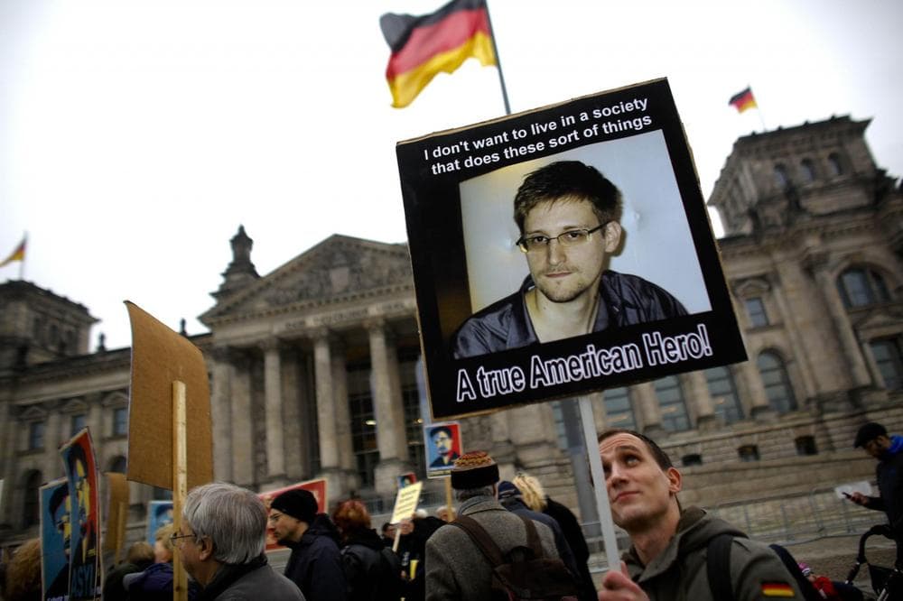 Protesters hold posters of former National Security Agency member Edward Snowden in front of the German parliament building, the Reichstag, prior to a special meeting of the parliament on US-German relationships, in Berlin, Monday, Nov. 18, 2013. (AP)