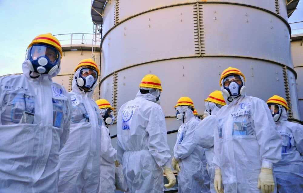 In this photo released Nov. 27, 2013, by International Atomic Energy Agency, a team of IAEA experts check out water storage tanks at the crippled Fukushima Dai-ichi nuclear power plant in Okuma, Japan. (Greg Webb/IAEA)