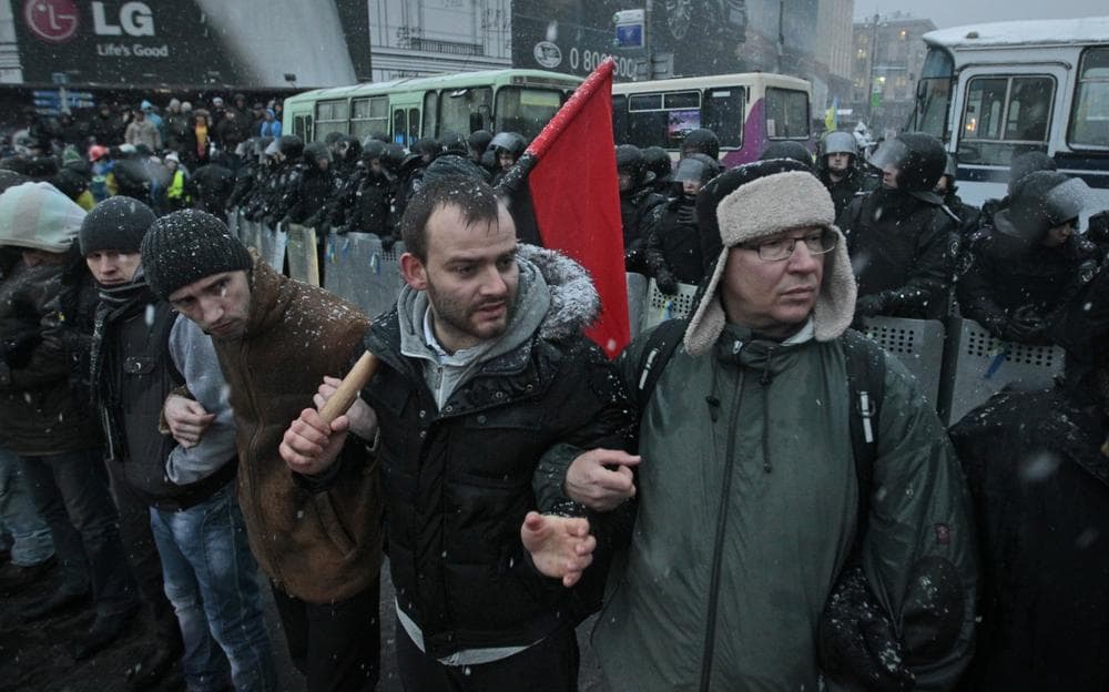 Pro-European Union activists stand with their backs towards police, in front of the police line to prevent provocations near the Independence Square in Kiev, Ukraine, Monday, Dec. 9, 2013. (Sergei Chuzavkov/AP)