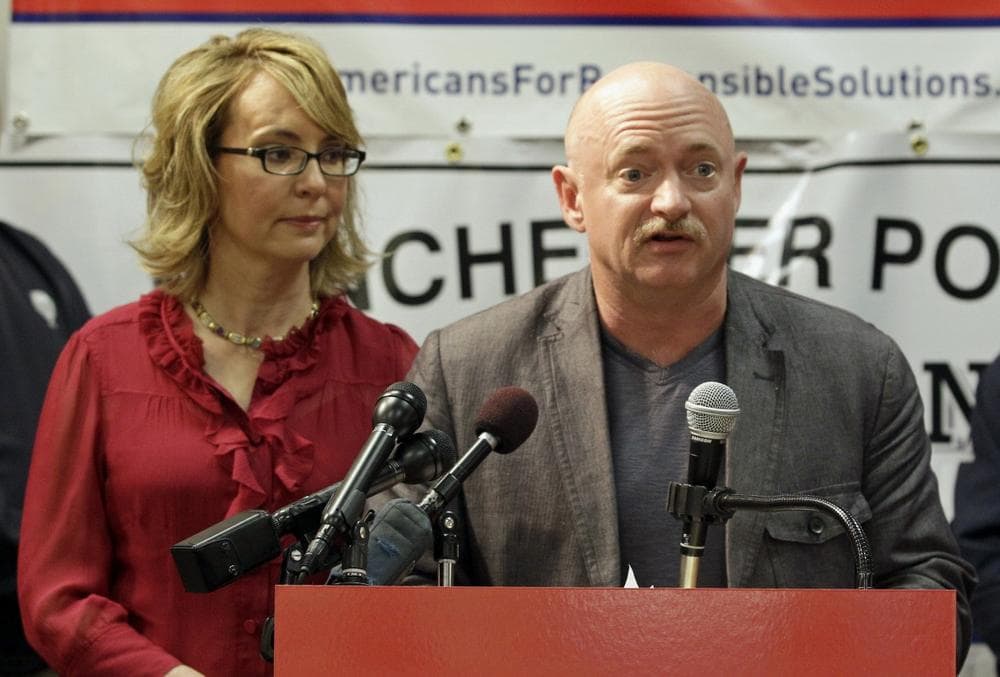 Former Arizona Rep. Gabrielle Giffords listens as her husband retired astronaut and combat veteran Captain Mark Kelly speaks during a news conference at the Millyard Museum, Friday, July 5, 2013 in Manchester, N.H. (Mary Schwalm/AP)