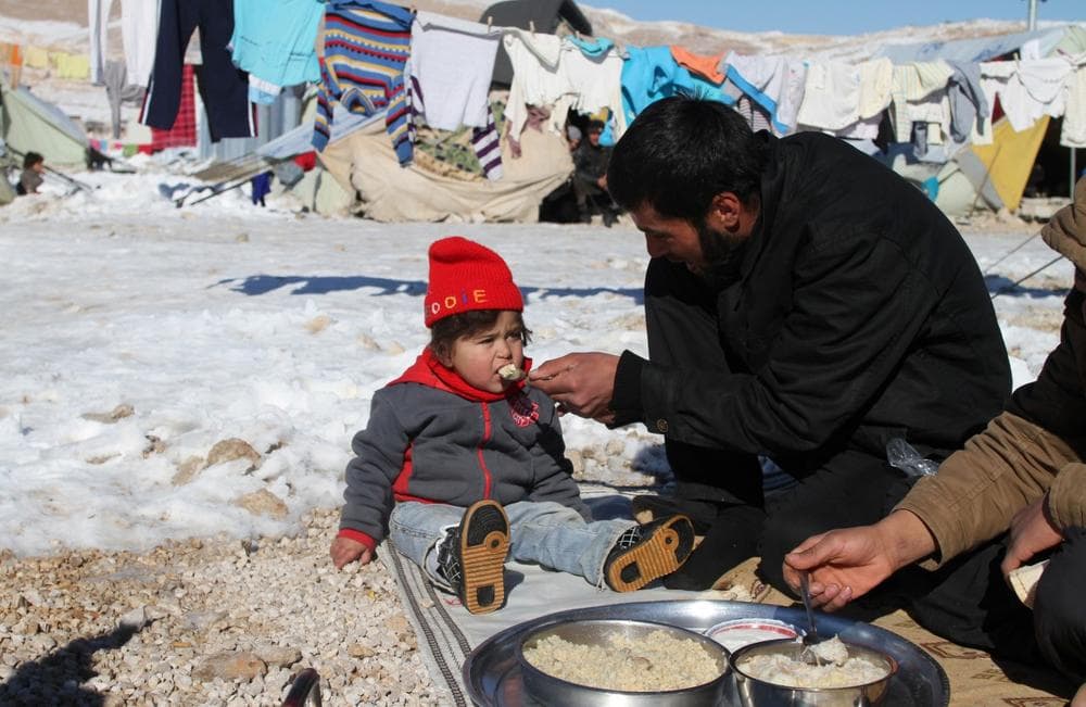 A Syrian man feeds his child in the Arsal refugee camp in the Lebanese Bekaa valley on December 15, 2013. (AFP/Getty Images)