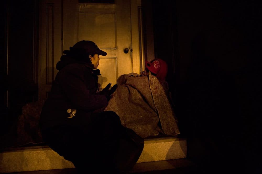During the city's 2013 homeless census, Elisabeth Jackson, executive director of Bridge Over Troubled Waters, asks a man sleeping in a doorway if he needs assistance. (Jesse Costa/WBUR)