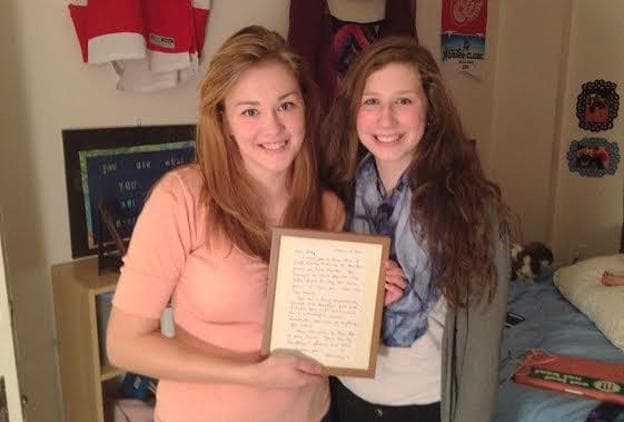 Kelly Rothe and her younger sister, Samantha. They're holding a letter written for Kelly by their mother before she died. (Kate Wells/Michigan Radio)