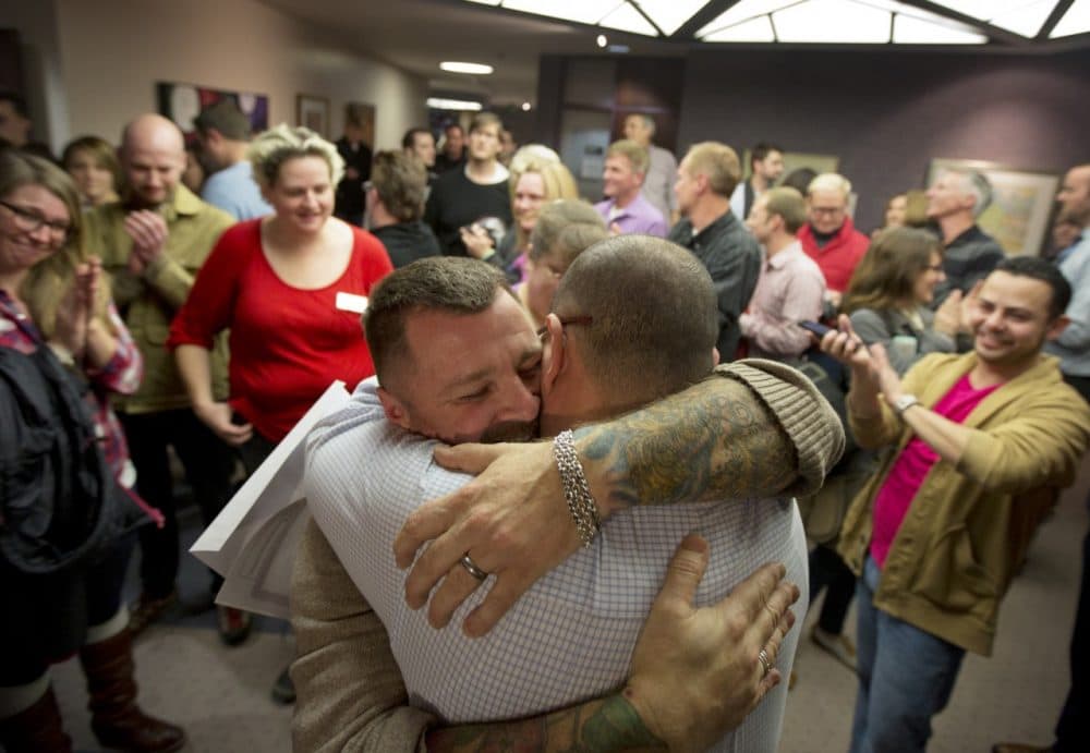 Chris Serrano, left, and Clifton Webb embrace after being married, as people wait in line to get licenses outside of the marriage division of the Salt Lake County Clerk's Office in Salt Lake City, Friday, Dec. 20, 2013. (Kim Raff/AP)