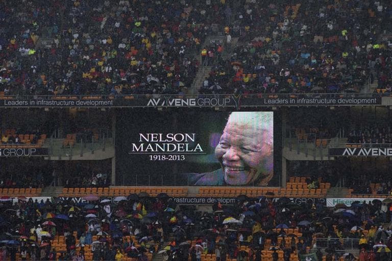 Spectators shelter under umbrellas as the rain lashes down during the memorial service for former South African president Nelson Mandela at the FNB Stadium in Soweto, near Johannesburg, South Africa, Tuesday Dec. 10, 2013. (AP)