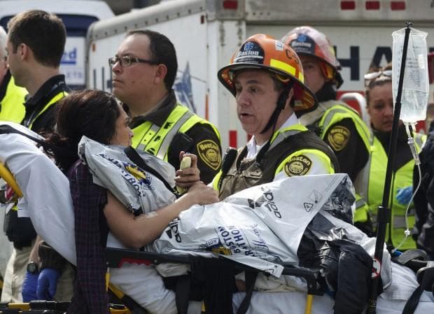 Emergency responders comfort a woman on a stretcher who was injured in one of the blasts near the Boston Marathon finish line. (Jeremy Pavia/AP)