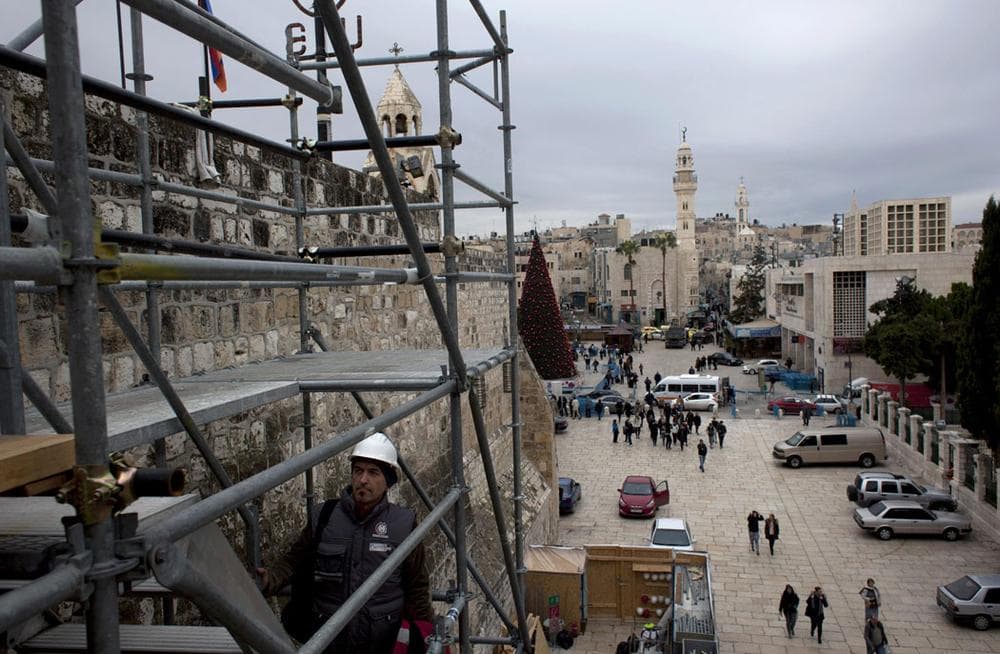 Tourists walk around the Church of the Nativity in the West Bank city of Bethlehem on Dec. 10, 2013. Wrapped in scaffolding, the basilica is having a much-needed facelift after 600 years. Last year it was included in UNESCO's list of endangered World Heritage sites. (AP Photo/Nasser Nasser)