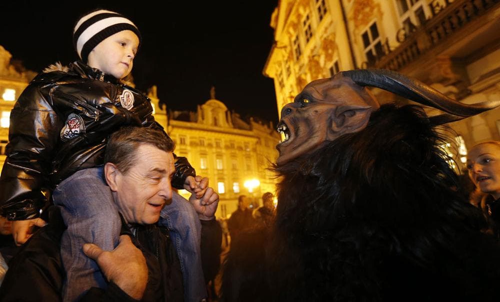 A man dressed as a devil scares a boy during a St. Nicholas parade at the Old Town Square in Prague, Czech Republic, on Dec. 5, 2012. During this traditional procession people dressed as St. Nicholas, angels and devils reward well-behaved children with small presents. (AP Photo/Petr David Josek)