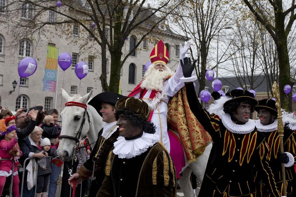People line a road to watch the arrival of Sinterklaas, the Dutch version of Santa Claus, and his blackface sidekicks &quot;Zwarte Piet,” or &quot;Black Pete,&quot; in Amsterdam, Netherlands, on Nov. 17, 2013. Critics charge that Black Petes are an offensive caricature of black people while proponents say Pete is a figure of fun whose appearance is harmless, his face soot-stained from going down chimneys to deliver presents for the children. (AP Photo/Peter Dejong)