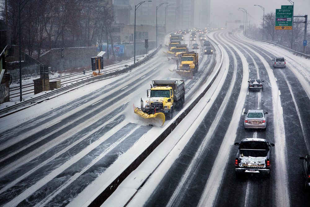 A row of snow plows moves down I-90 in Boston. (Jesse Costa/WBUR)