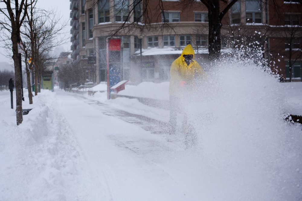 A man uses a snowplow on a sidewalk along Comm Ave in Boston Friday morning. 