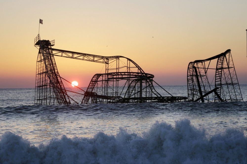 The sun rises in Seaside Heights, N.J. behind the Jet Star Roller Coaster which has been sitting in the ocean after part of the Funtown Pier was destroyed during Superstorm Sandy. (Mel Evans/AP)