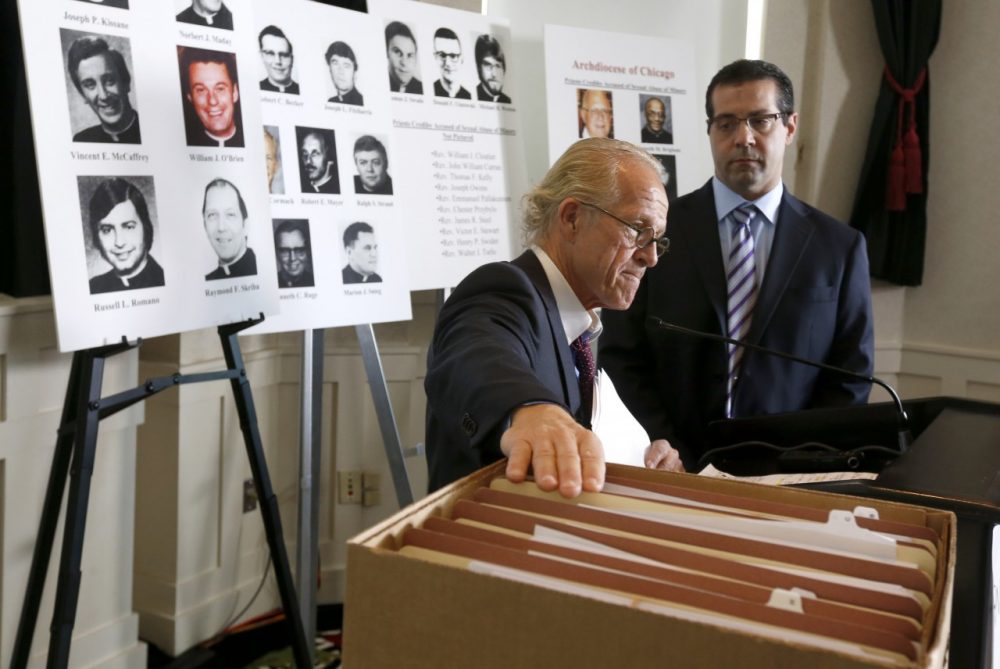 Attorney Jeff Anderson, left, places his hand on the files of Catholic priests credibly accused of sexually abusing minors in the Archdiocese of Chicago, prior to a news conference Tuesday, Jan. 21, 2014, in Chicago. Joining Anderson is attorney Marc Pearlman. (Charles Rex Arbogast/AP)