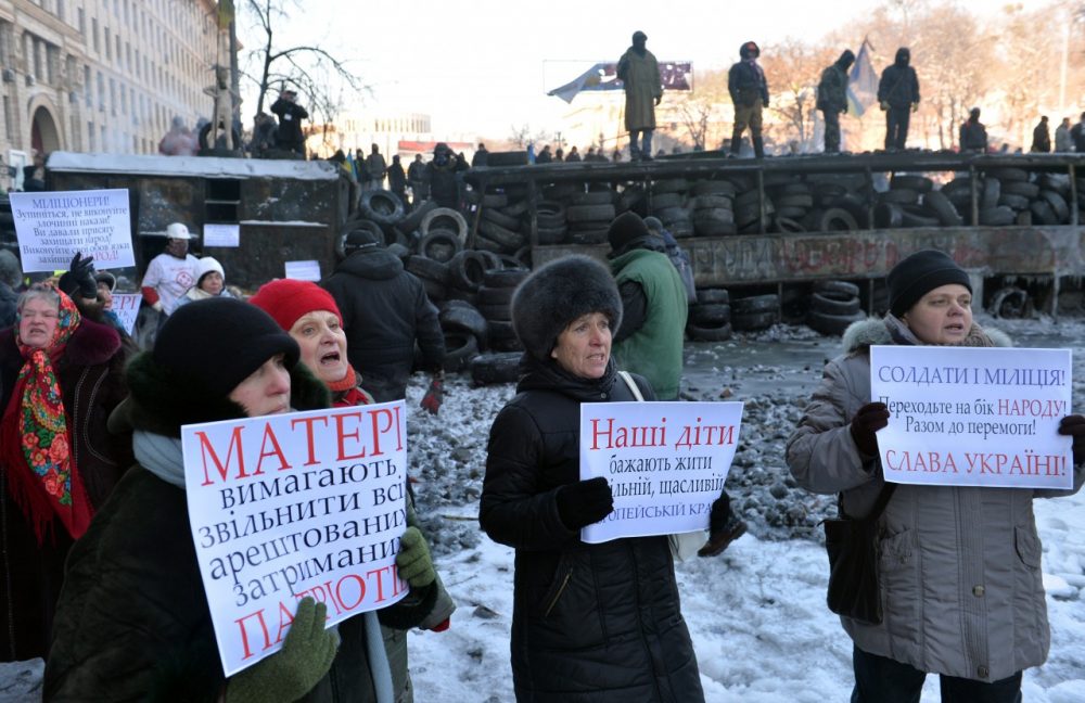 Women hold placards calling police to stop blood-letting and join protesters as they stay in front of the police line in Kiev on January 24, 2014. (Sergei Supinsky/AFP/Getty Images)