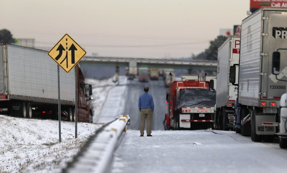A man stands on the frozen roadway as he waits for traffic to clear along Interstate 75 Wednesday, Jan. 29, 2014, in Macon, Ga. (John Bazemore/AP)