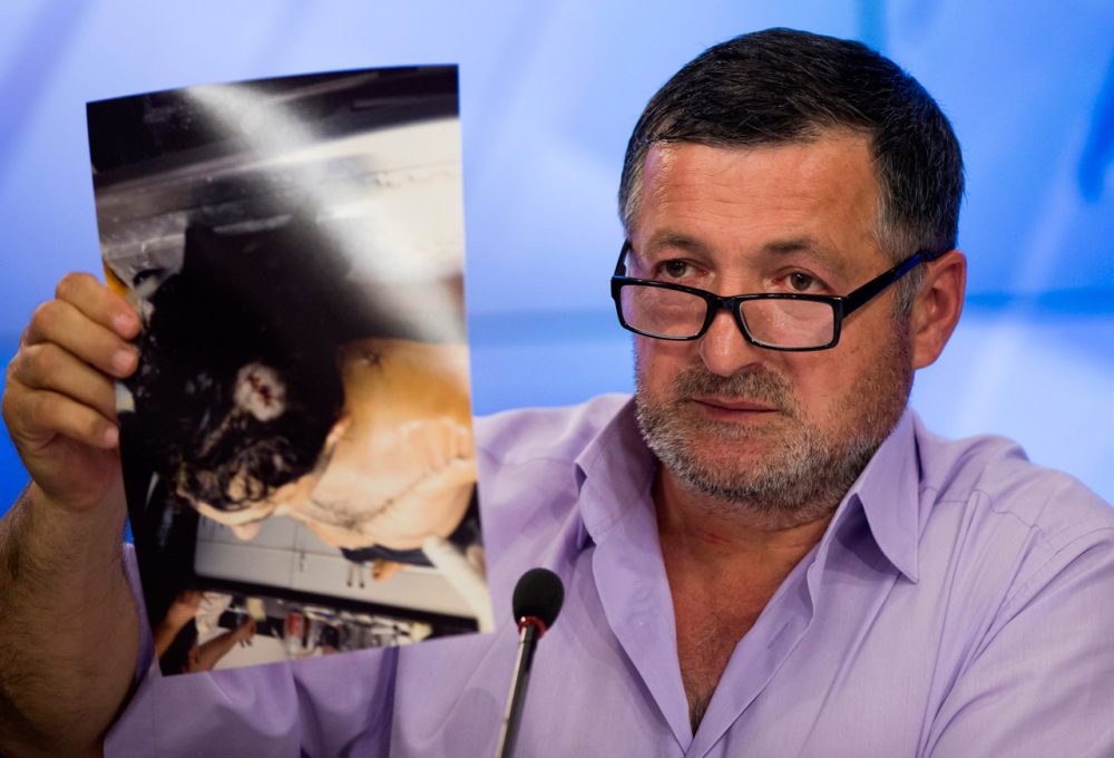 Abdul-Baki Todashev holds a photo he claims is of his dead son, Ibragim, during a news conference in Moscow, Russia, on May 30, 2013. The father, who says agents killed his son “execution style,” showed journalists 16 photographs of Ibragim in the morgue with what he said were six gunshot wounds to his torso and one to the back of the head. (Alexander Zemlianichenko/AP)
