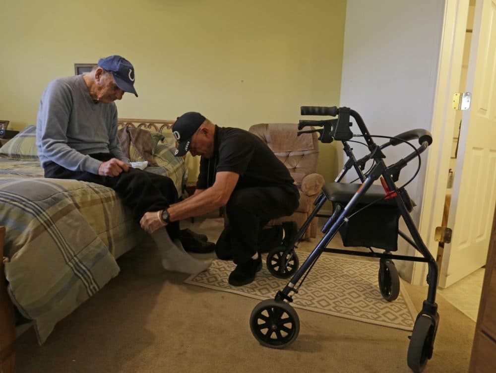 Caregiver Warren Manchess helps Paul Gregoline with his shoes and socks, in Noblesville, Ind. (Darron Cummings/AP)