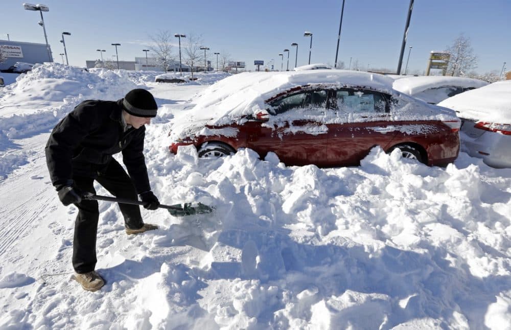 A car salesmen digs out cars covered in snow at a dealership in Indianapolis, Jan. 7, 2014, as temperatures hovered around zero. (Michael Conroy/AP)