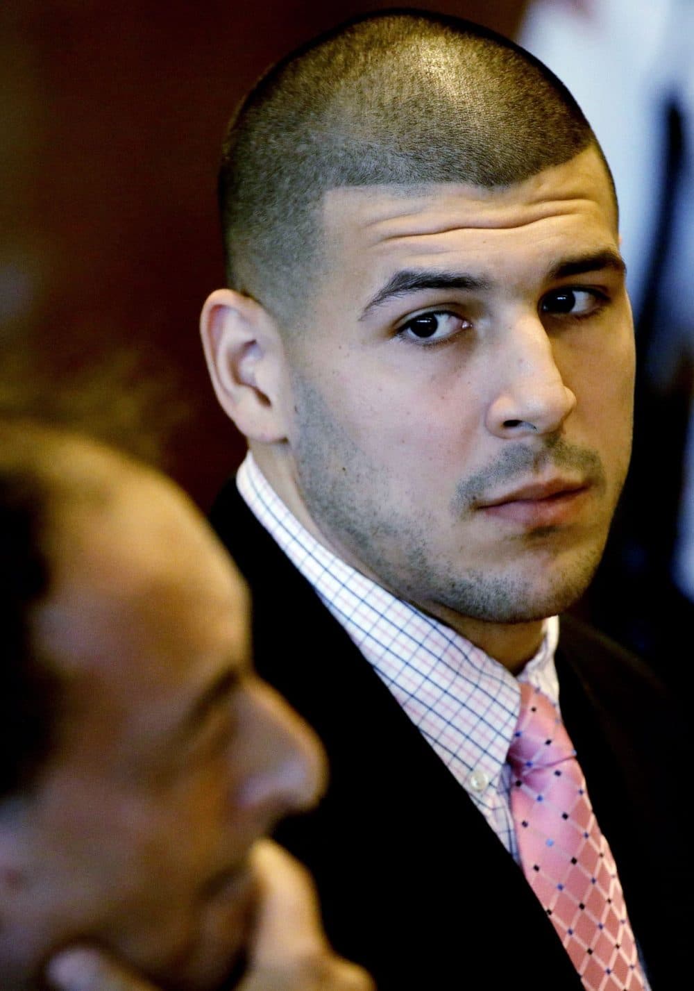 In this Oct. 21, 2013 file photo, former New England Patriot football player Aaron Hernandez looks to one of his attorneys, James Sultan, during a hearing in Bristol Superior Court in Fall River, Mass. Hernandez has pleaded not guilty to the murder of Odin Lloyd, whose body was found June 17 near Hernandez's home in North Attleborough, Mass. A search warrant filed in Connecticut in December 2013 shows police believe Hernandez was in an SUV when someone inside shot two people to death in Boston in 2012. In searching a home of Hernandez's uncle in Bristol, Conn., in June, police found the SUV wanted in the 2012 shooting in Boston. (Stephan Savoia/AP)