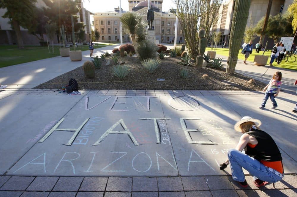 Margaret Jean Plews works on a chalk drawing as she joined nearly 250 gay rights supporters protesting SB1062 at the Arizona Capitol, Friday, Feb. 21, 2014, in Phoenix. (AP)
