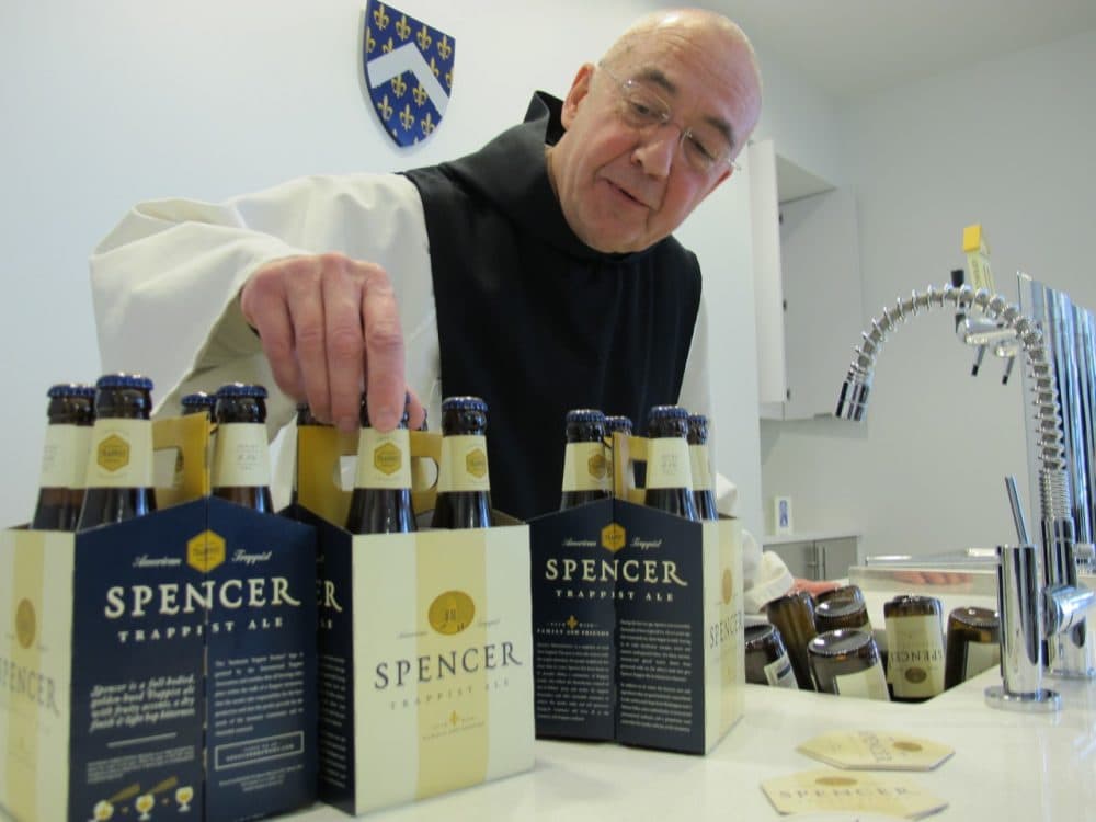 Fr. Isaac Keeley straightens the labels of the new Spencer Trappist Ale brewed at St. Joseph's Abbey in Spencer, Mass. (WBUR/Kathleen McNerney)