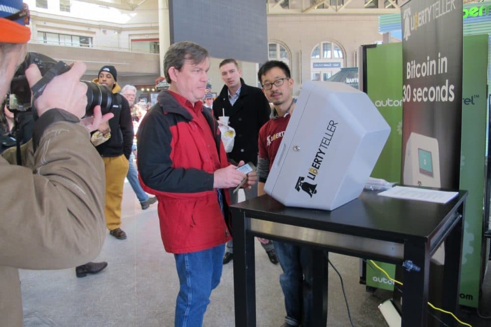 Paul Watts of Newton tries out the bitcoin kiosk at South Station while Liberty Teller co-founder Chris Yin helps. (Anna Taylor/WBUR)