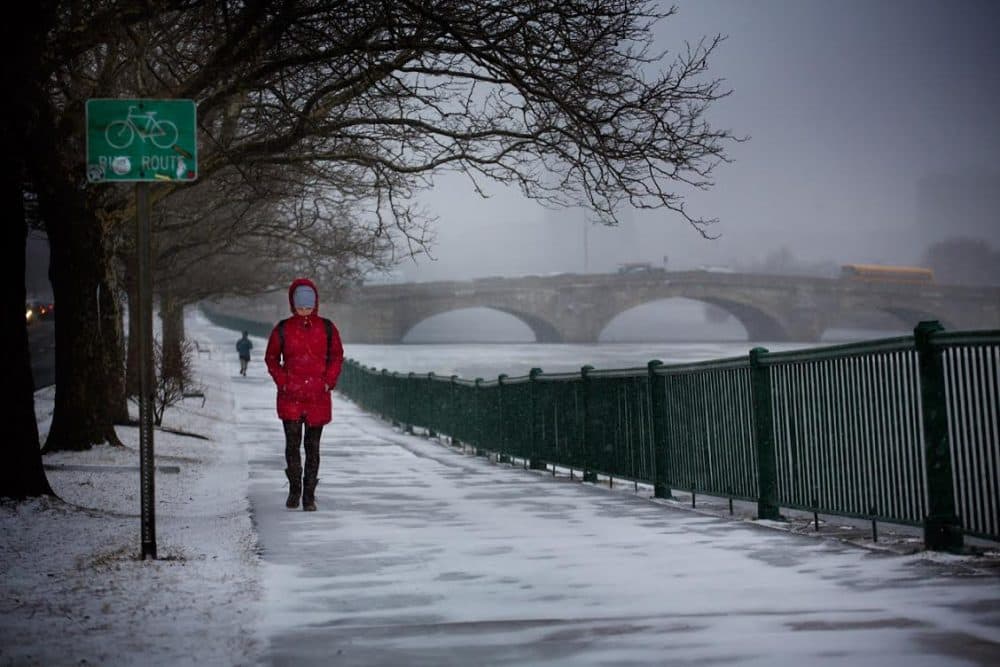 Woman walks on Memorial Drive along the Charles River. (Jesse Costa/WBUR)