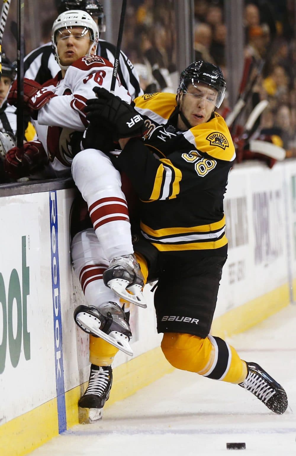 Boston Bruins' Jordan Caron checks Phoenix Coyotes' Rob Klinkhammer into the boards during the third period of Boston's 2-1 win in an NHL hockey game in Boston Thursday, March 13, 2014. (Winslow Townson/AP)
