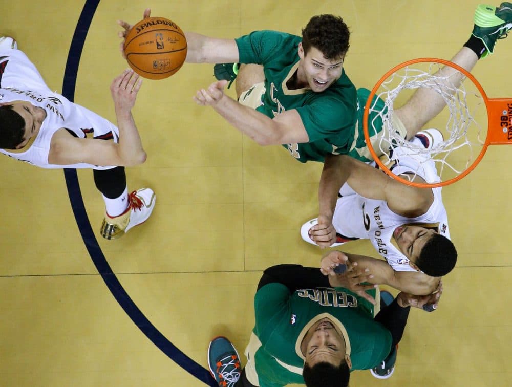 Boston Celtics center Kris Humphries, top, goes to the basket against Pelicans forward Anthony Davis, right, and  guard Austin Rivers, left. (Jonathan Bachman/AP)