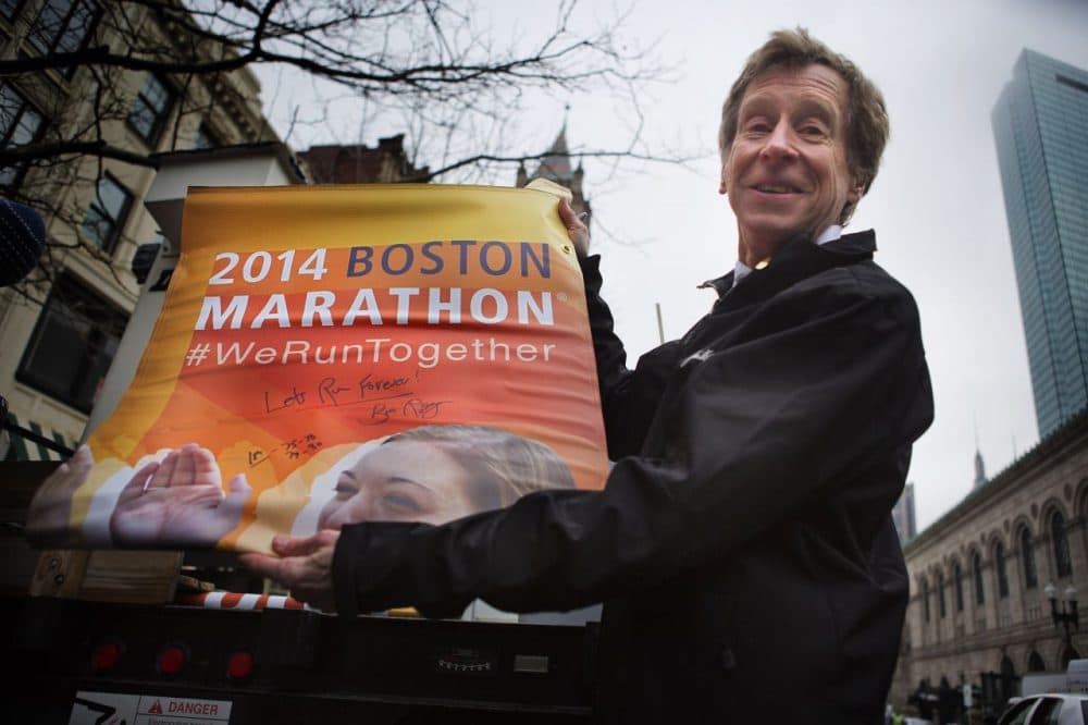 Bill Rodgers presenting a banner he signed. (Jesse Costa/WBUR)