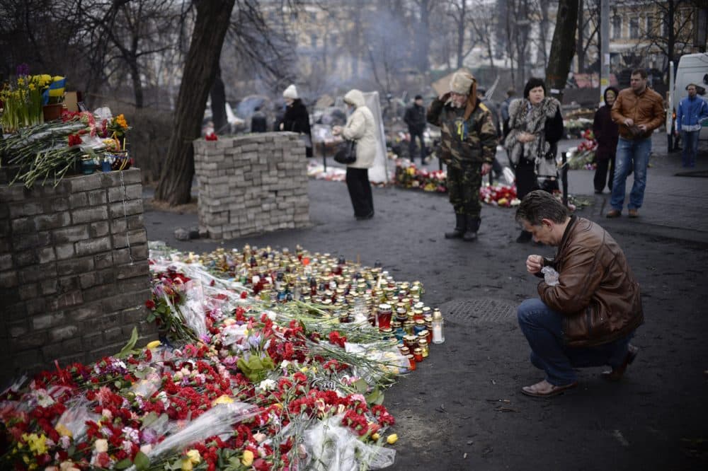People pay their respects at a makeshift memorial where a protester was killed during clashes with police near Independence Square  The Ukrainian government has promised justice for the fallen, but citizens in Kiev remain uneasy. (Dimitar Dilkoff/AFP/Getty Images)