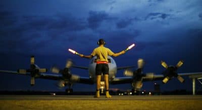 A ground controller guides a Royal Australian Air Force AP-3C Orion to rest after sunset upon its return from a search for the missing Malaysia Airlines flight MH370 over the Indian Ocean, at the Royal Australian Air Force base Pearce in Perth, Monday, March 24, 2014. New analysis of satellite data indicates the missing plane crashed into a remote corner of the Indian Ocean. (Jason Reed/AP)