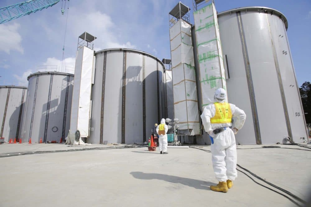 A worker in a protective suit and a mask looks at tanks, under construction, to store radioactive water, in the J1 area at the Tokyo Electric Power Co's (TEPCO) tsunami-crippled Fukushima Dai-ichi nuclear power plant in Okuma, Fukushima prefecture, northeastern Japan, Monday, March 10, 2014. (AP)
