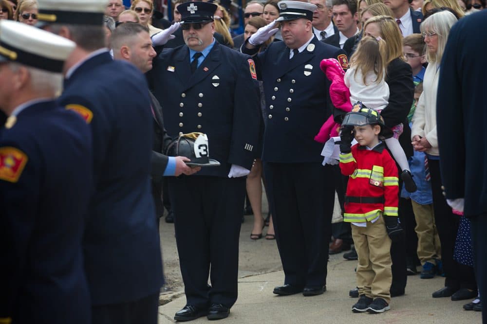 Robbie Malone, Lt. Ed Walsh's nephew, salutes as Lt. Walsh's helmet is carried into St. Patrick's Church. (Jesse Costa/WBUR)