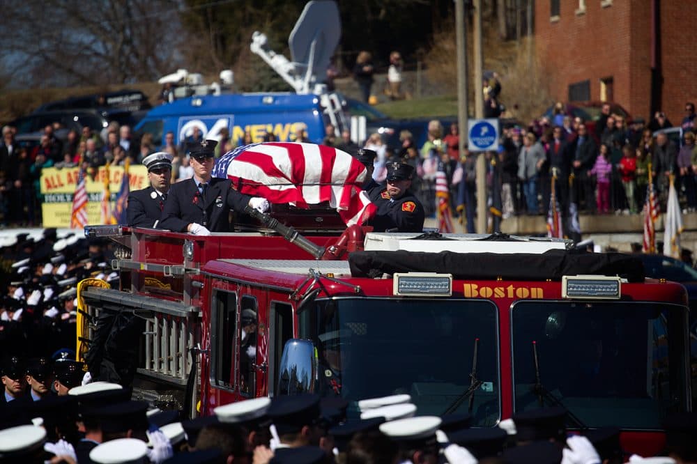 Firefighter Michael Kennedy’s casket is brought on Engine 33 to West Roxbury’s Holy Name Church on Thursday. (Jesse Costa/WBUR)