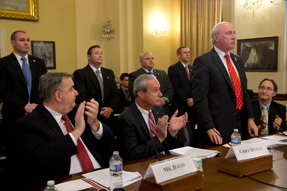 Ex-Boston Police Commissioner Ed Davis, left, and Watertown Police Chief Edward Deveau, center, applaud as Watertown Police Sgt. Jeffrey Pugliese and fellow Watertown officers are acknowledged during a Capitol Hill hearing Wednesday. (Jacquelyn Martin/AP)