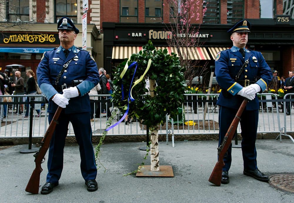 Police honor guard stands with a wreath outside The Forum, the site where the second bomb exploded at last year's Boston Marathon. (Joe Spurr/WBUR)