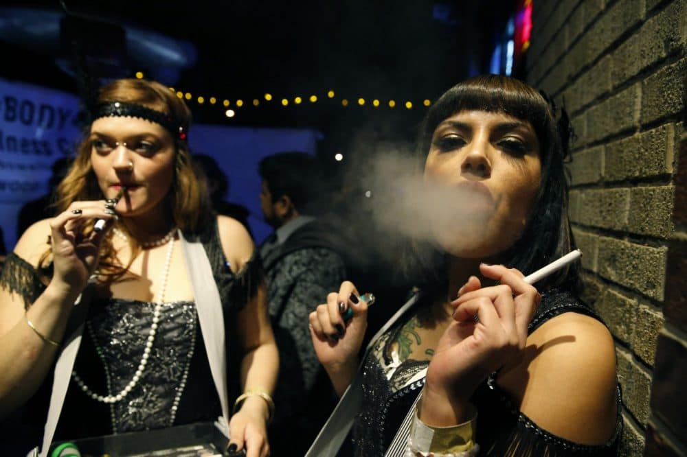Partygoers smoke marijuana and cigarettes during a Prohibition-era themed New Year's Eve party celebrating the start of retail pot sales, at a bar in Denver. (Brennan Linsley/AP)