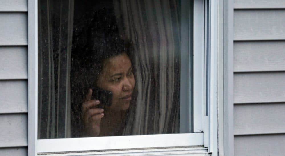 A woman looks out a window at her home as police start to search an apartment building while looking for a suspect in the Boston Marathon bombings in Watertown, Mass., Friday, April 19, 2013. (Charles Krupa/AP)