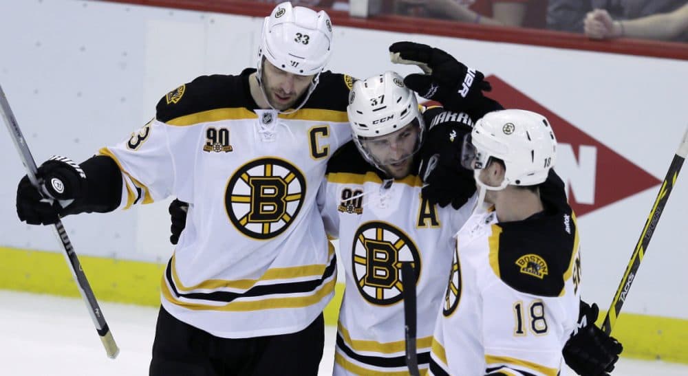 Boston Bruins defenseman Zdeno Chara, left, and right wing Reilly Smith, congratulate center Patrice Bergeron after his empty net goal during the third period of Game 3 of a first-round NHL hockey playoff series against the Detroit Red Wings in Detroit, Tuesday, April 22, 2014. (Carlos Osorio/AP)