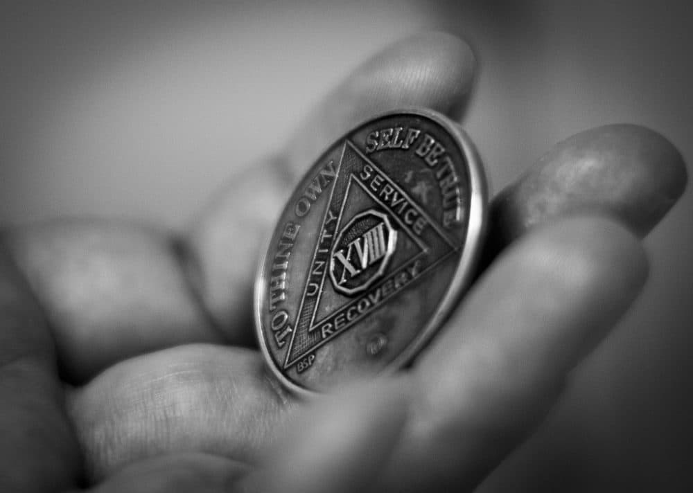 A man holds a chip AA members receive to mark sobriety. (Bernardo Fuller/Flickr)
