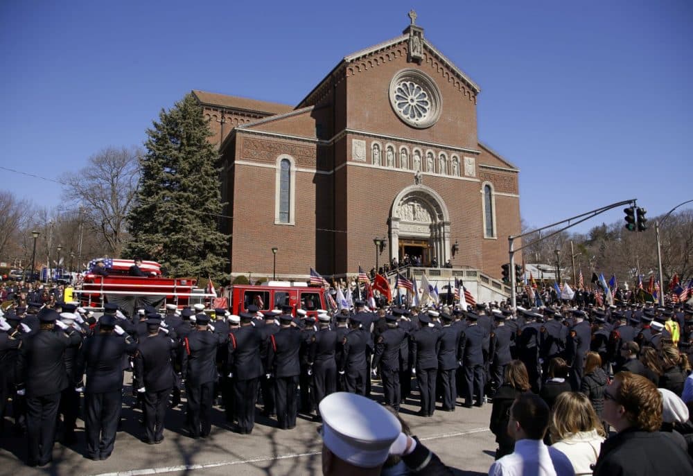 The funeral procession for Boston firefighter Michael R. Kennedy proceeds through saluting firefighters as it arrives at Holy Name Church in Boston, Thursday, April 3, 2014. Kennedy and Boston Fire Lt. Edward J. Walsh were killed Wednesday, March 26, 2014 when they were trapped in the basement of a burning brownstone during a nine-alarm blaze. (AP)
