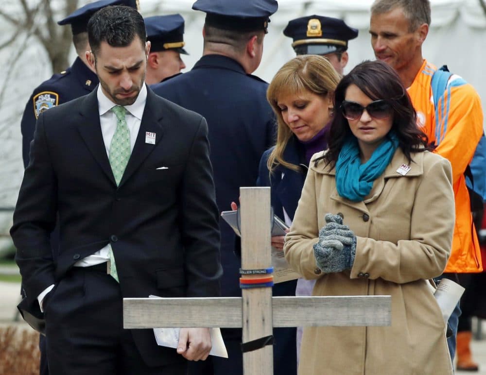 Police officers, friends and family members pause by a memorial cross and stone after attending a one-year remembrance ceremony for Massachusetts Institute of Technology Officer Sean Collier on campus in Cambridge, Mass., Friday, April 18, 2014. Authorities say Collier was slain by the suspects of the 2013 Boston Marathon bombing. (AP)