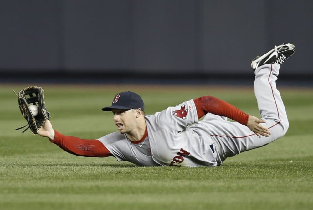 Boston Red Sox right fielder Daniel Nava shows the ball to the umpire after making a sliding catch on a third-inning fly-out hit by New York Yankees' Yangervis Solarte in a baseball game at Yankee Stadium in New York, Thursday, April 10, 2014. (Kathy Willens/AP)