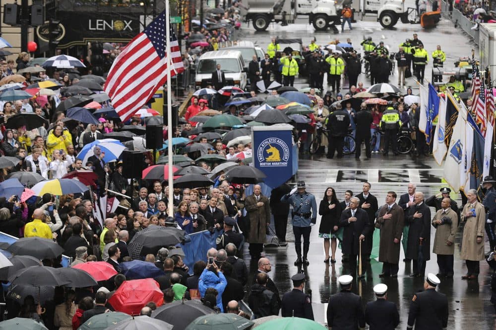 Survivors, officials, first responders and guests pause as the flag is raised at the finish line during a tribute in honor of the one year anniversary of the Boston Marathon bombings, Tuesday, April 15, 2014 in Boston. (AP)