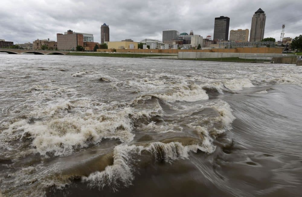 Water splashes over the Center Street Dam in the swollen Des Moines River in downtown Des Moines, Iowa. Climate change's assorted harms &quot;are expected to become increasingly disruptive across the nation throughout this century and beyond,&quot; the National Climate Assessment concluded Tuesday. (Charlie Neibergall/AP)
